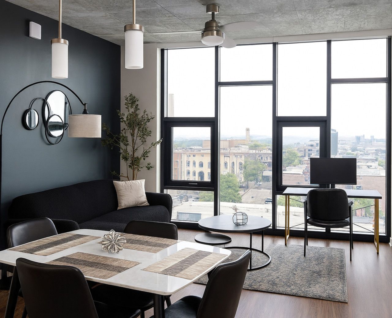 A modern living room with a large window, a sofa, a dining table, and a TV.