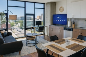 A modern living room with a sofa, a small round table, and a TV displaying the Disney logo. - Modern 2BR Gem | Rooftop Pool + Workspaces SH6 (Birmingham)