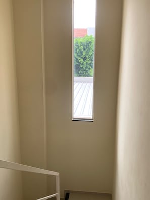 A room with a small window, a white ceiling, and a visible roofline. - Comfortable townhouse (Campo Grande)