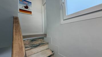 Una escalera con barandilla de madera, una ventana y un cuadro colgado en la pared.