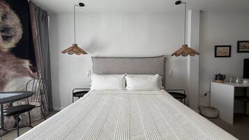 Un dormitorio con una cama grande, dos mesitas de noche, un escritorio y una lámpara colgante.