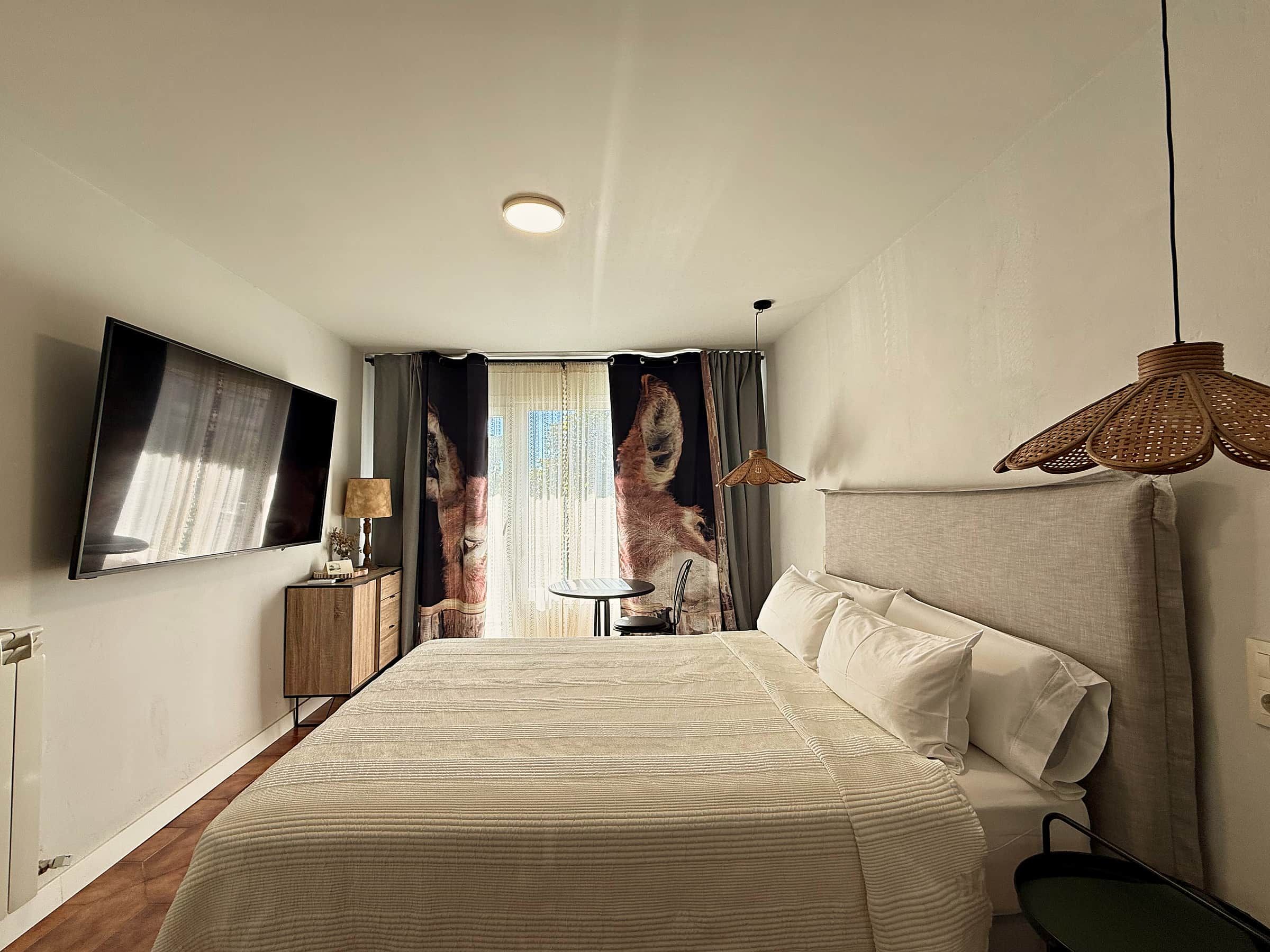 Dormitorio con cama doble, televisión y balcón a la plaza