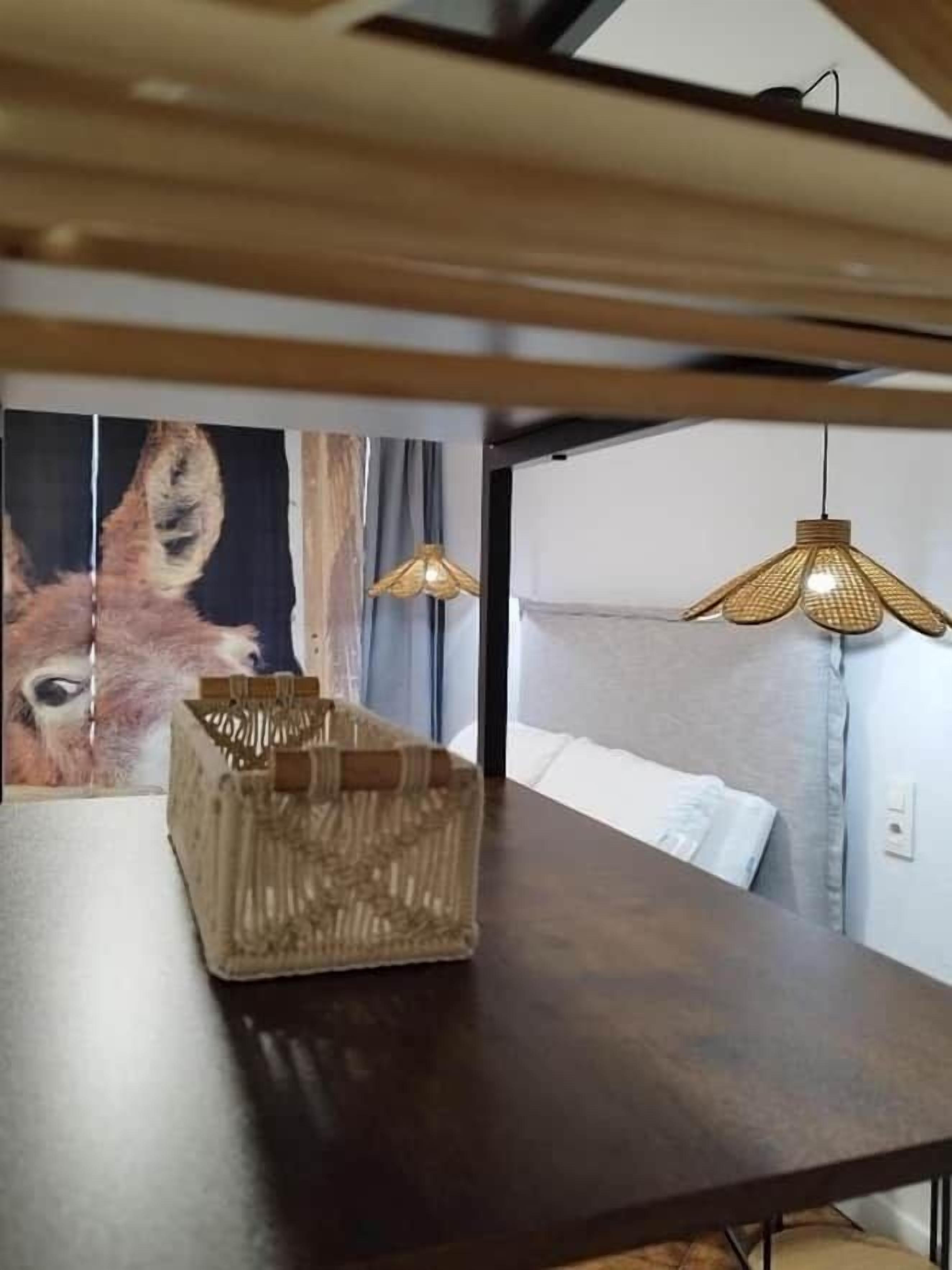 Una habitación con una mesa de madera oscura, una cesta tejida y dos lámparas colgantes.