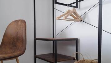 A corner of a room with a metal shelving unit, a brown chair, and a woven basket.