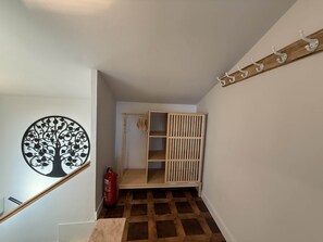 A staircase with a wooden handrail, a fire extinguisher, and a wall-mounted coat rack.
