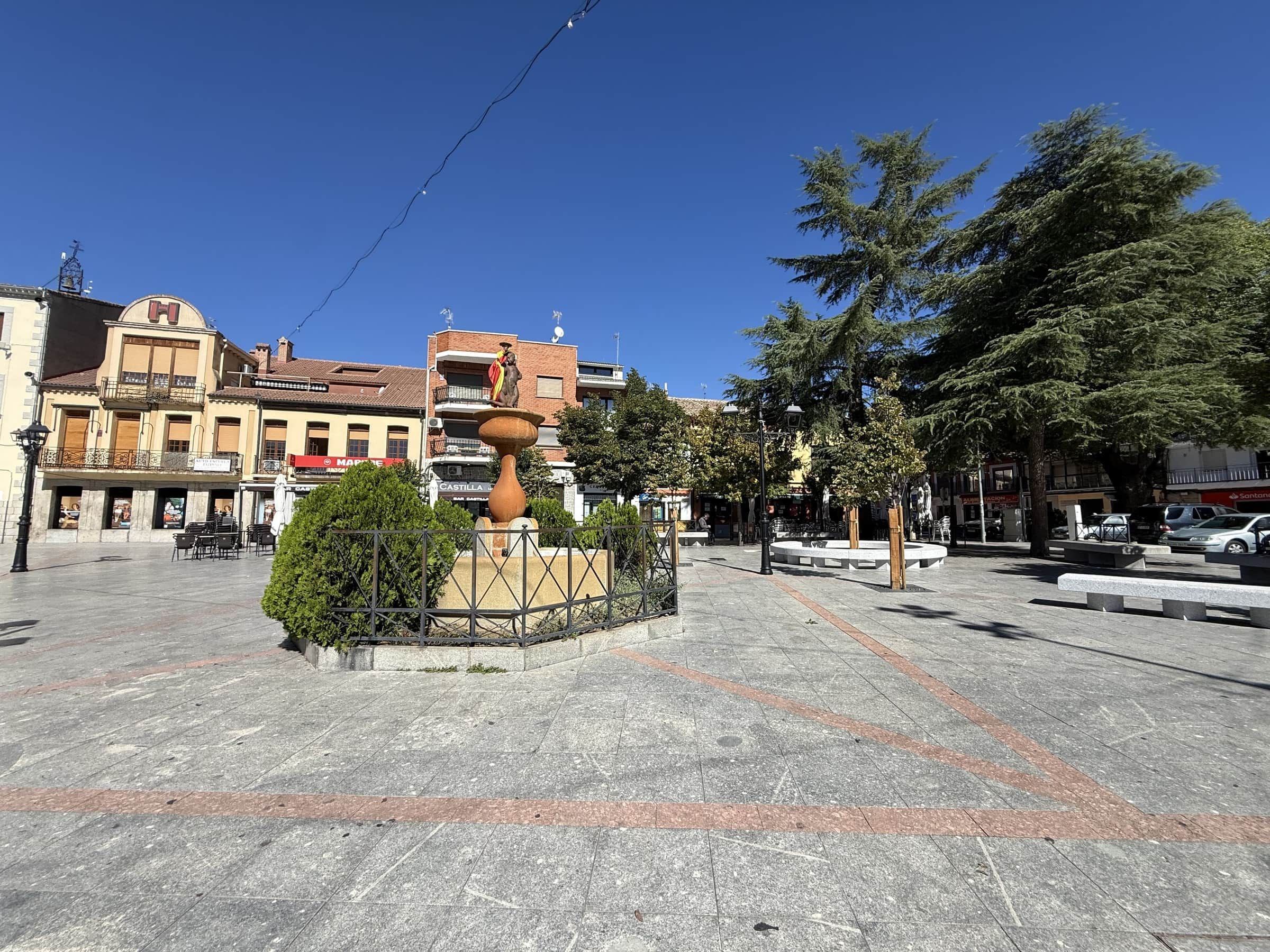 A public square with a fountain, seating areas, and surrounding buildings.