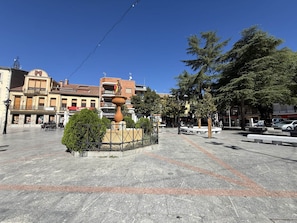 A public square with a fountain, seating areas, and surrounding buildings.