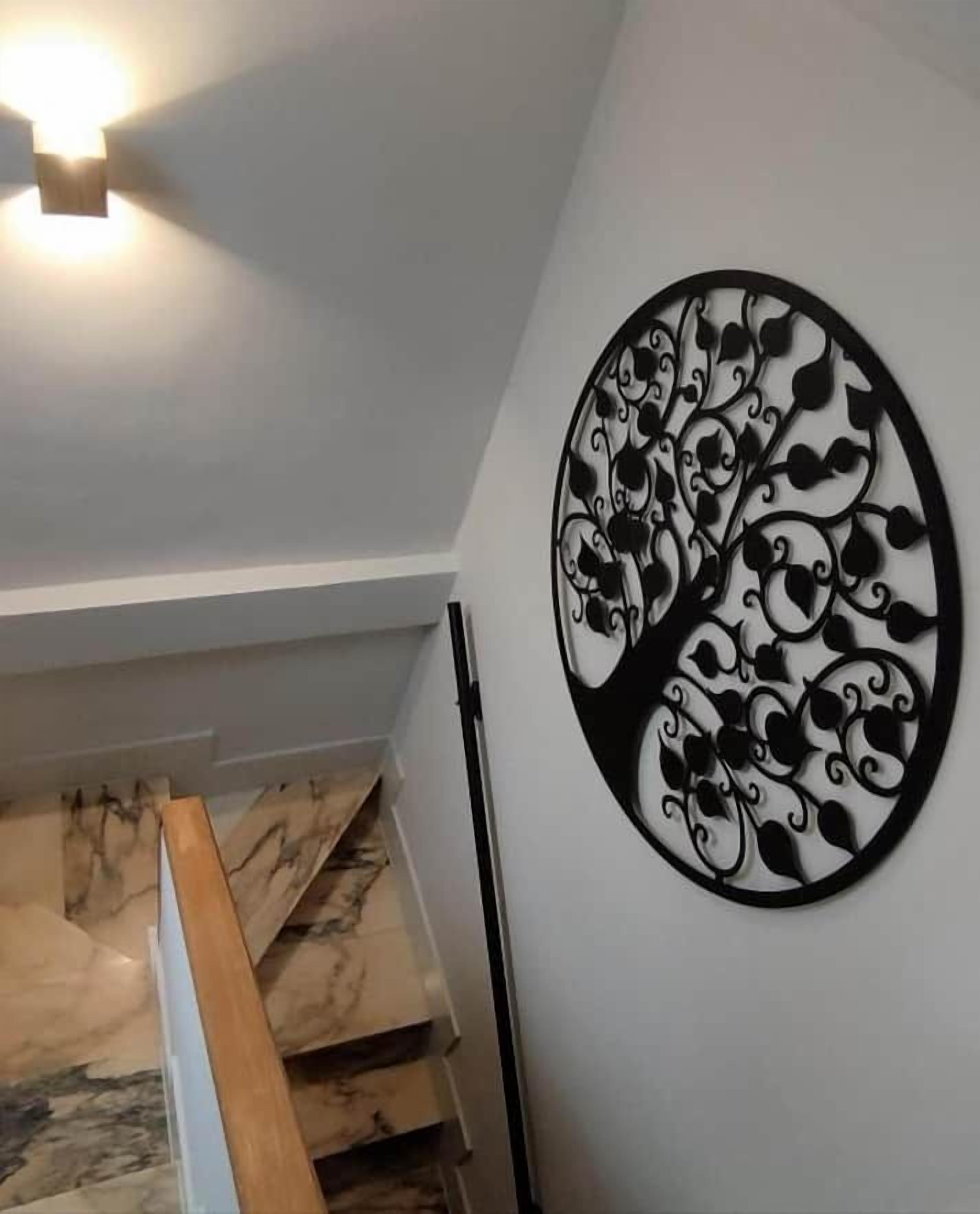 A staircase with a wooden handrail and a wall-mounted decorative metal piece.