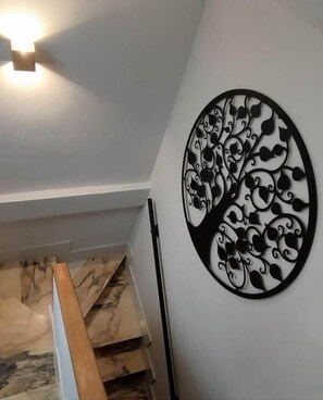 A staircase with a wooden handrail and a wall-mounted decorative metal piece. - Tree of Life · The Sky of Cebreros (Ávila) (Cebreros)