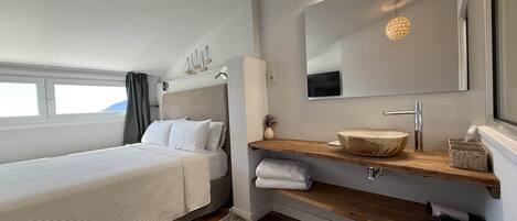 Un dormitorio moderno con una cama, un tocador de madera, un espejo y una ventana.