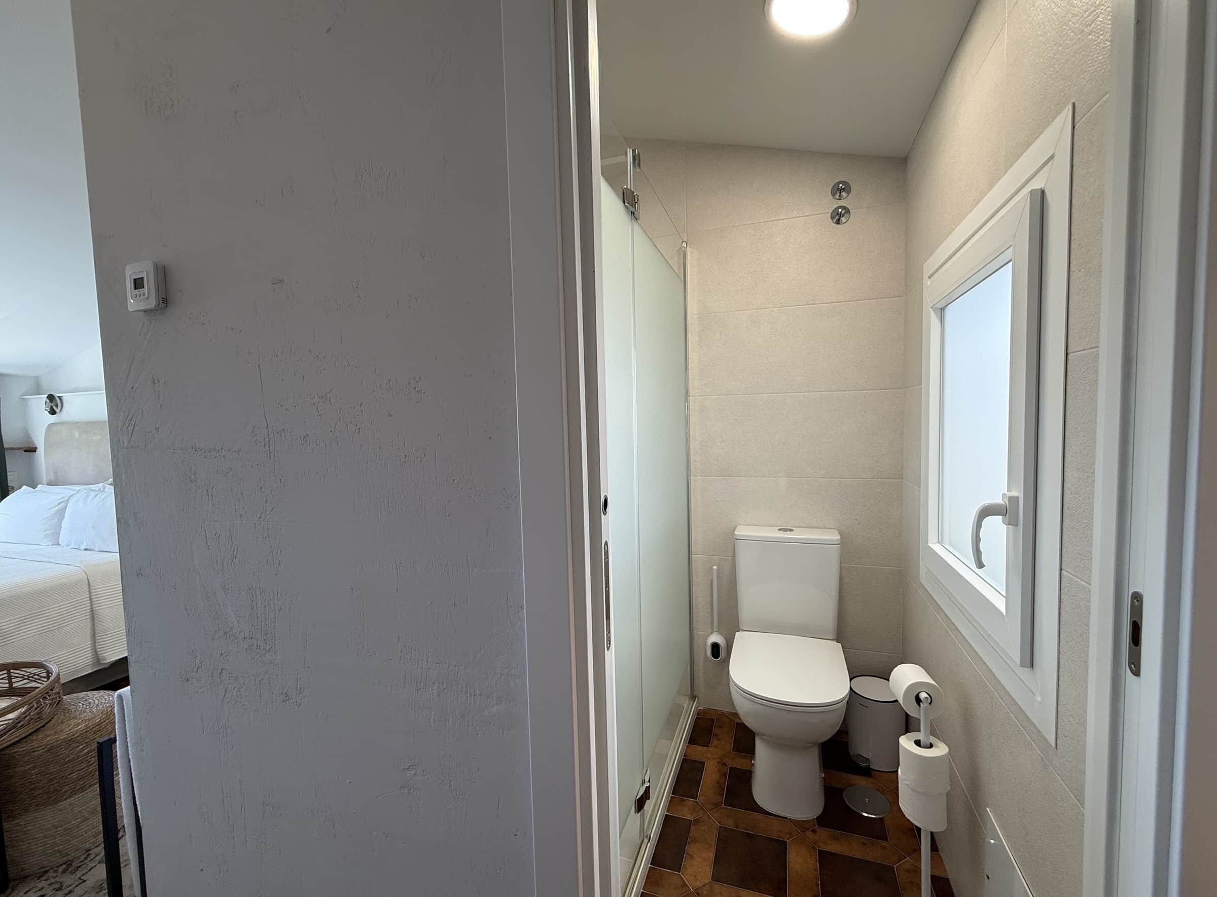 Un baño pequeño con inodoro, bidé y soporte para papel higiénico.