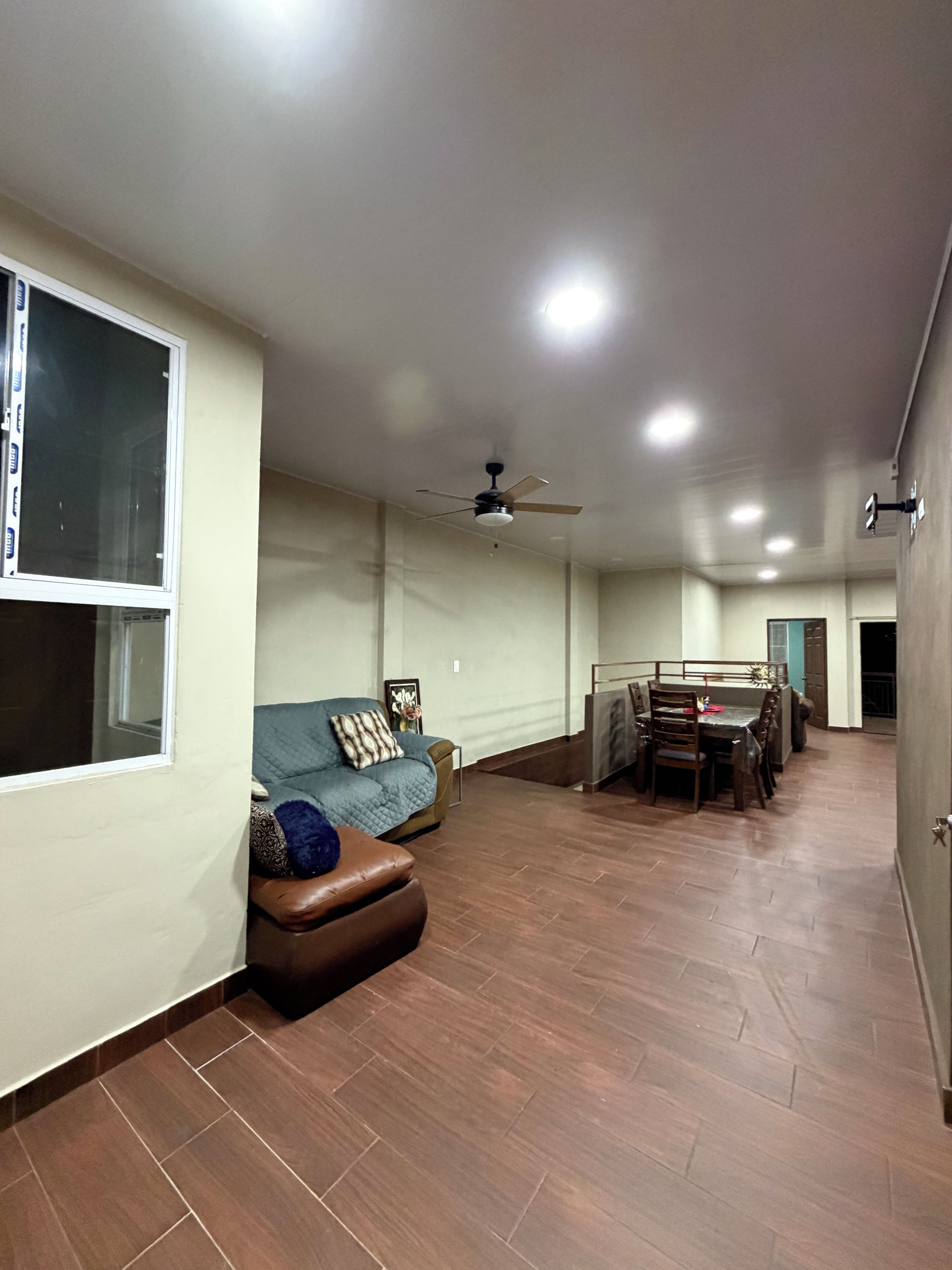 Un vaste espace de vie comprenant un canapé, une table à manger et un ventilateur de plafond.