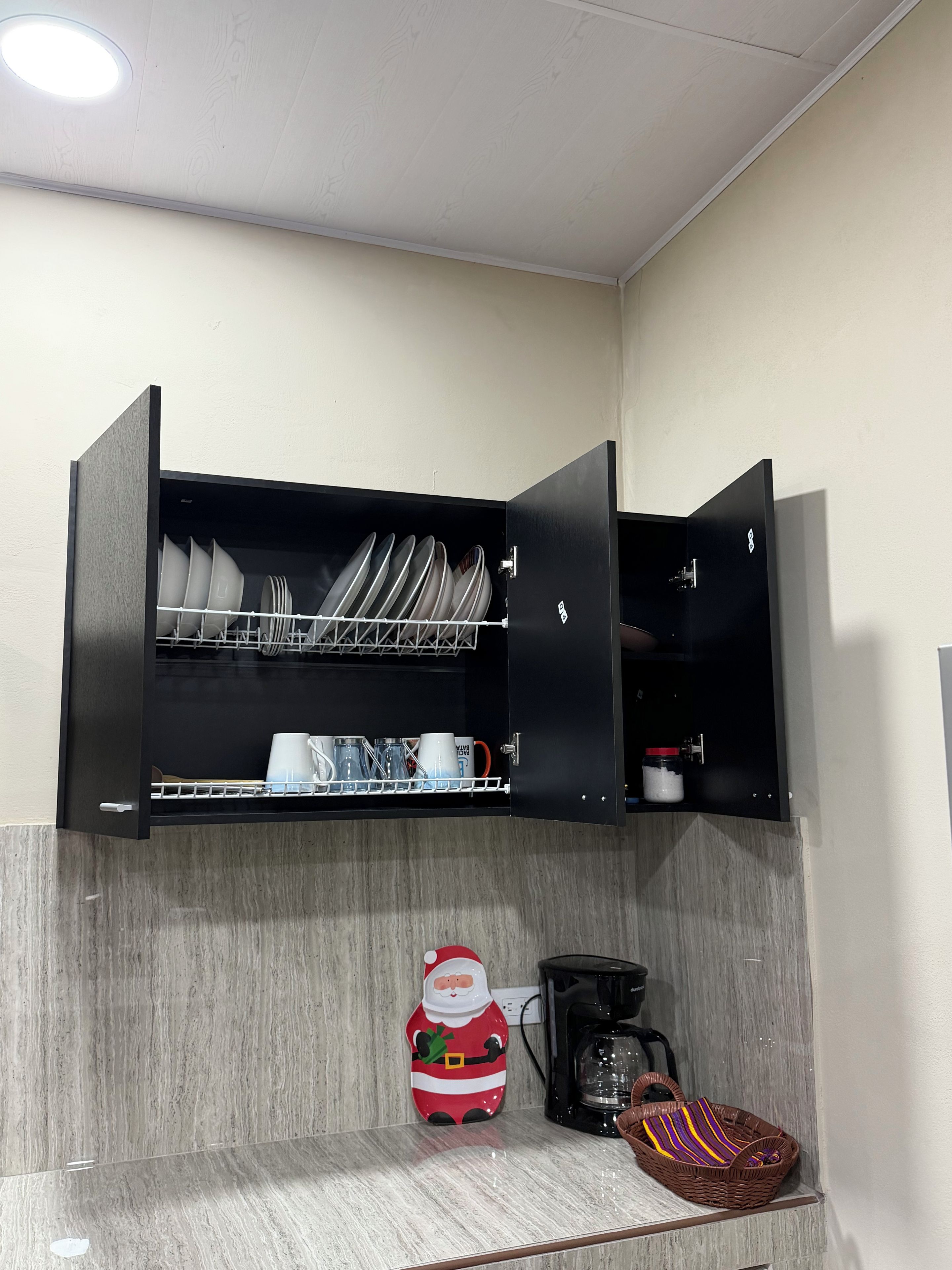 Una cucina con scolapiatti, macchina da caffè e una tazza a tema natalizio.