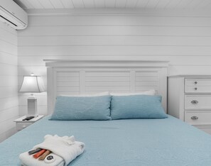 Et soveværelse med en seng, et natbord, en lampe og en kommode.