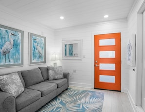 A living room with a gray sofa, a blue and white patterned rug, and two framed paintings of birds on the wall. - Miramar Beach 1BR • Prv Beach, Beach Service, Golf (Miramar Beach)