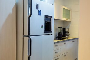 Una cocina con un refrigerador, una cafetera y una licuadora sobre la encimera.