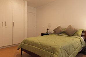 A bedroom with a bed, a nightstand, a vase with flowers, and a wardrobe. - Wonderful 2-bedroom apartment in the heart of Quito (Quito)