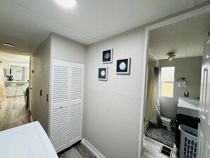 A hallway with a white closet, a kitchen area, and a bathroom with a shower and toilet. - Cozy 2-bedroom house in beautiful Bartow: 20m to Legoland, 1h to Disney & TPA (Bartow)