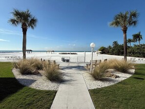 A beach pathway leading to a sandy beach with palm trees, lounge chairs, and a clear sky. - #1 Siesta Beach Paradise - Your Tropical Getaway on the Gulf in Siesta Key, FL (Sarasota)