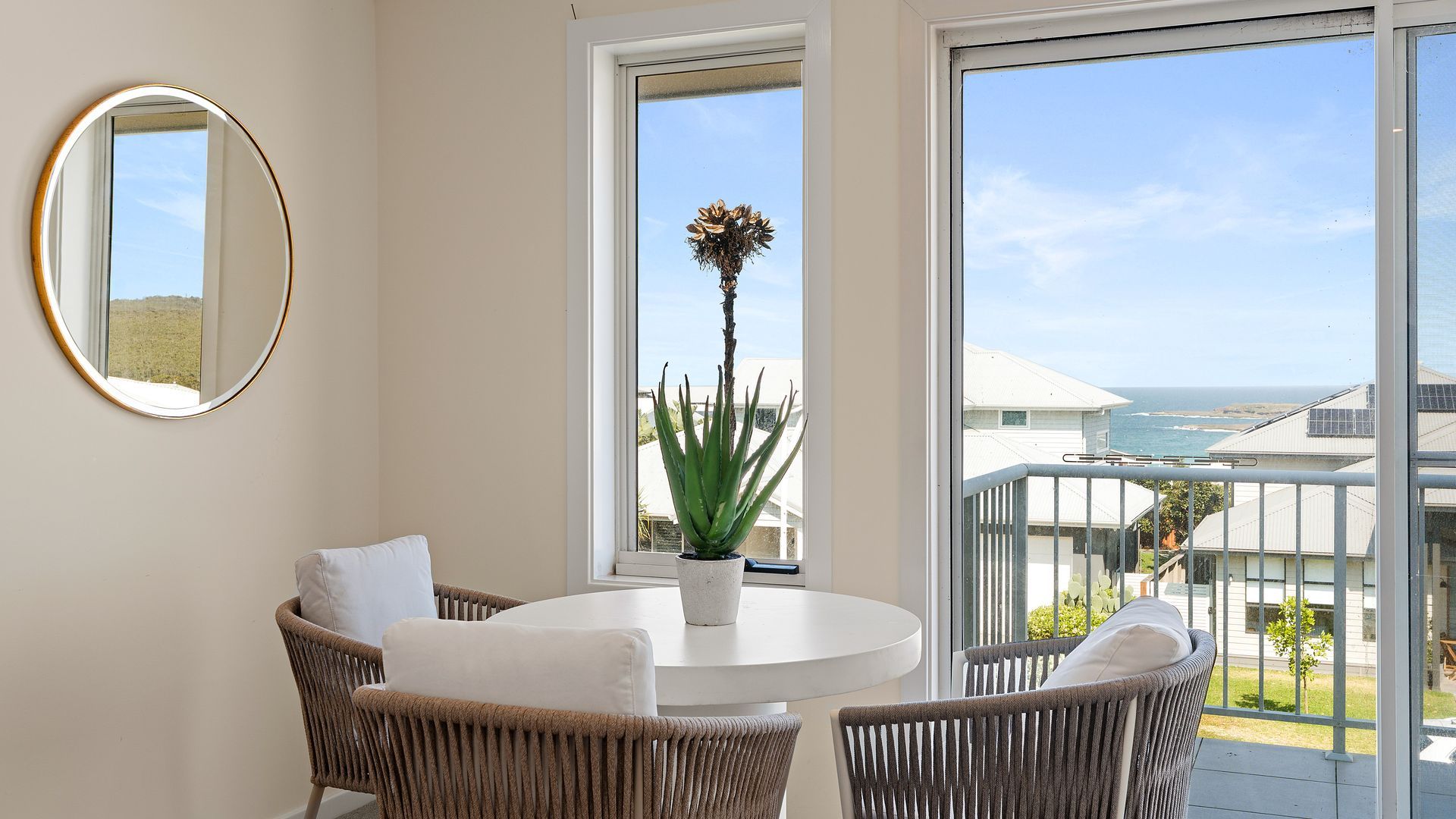 Bright sunlit sitting area featuring a round table, chairs, and scenic window outlook.   