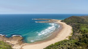 A coastal landscape with a sandy beach, clear blue waters, and dense green vegetation. - Catherine Hill Bay - Ocean Views & Coastal Living (Catherine Hill Bay)