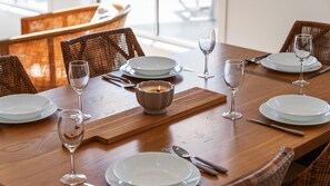 A dining table set with white plates, cutlery, and wine glasses, with a candle in a ceramic holder. - Catherine Hill Bay - Ocean Views & Coastal Living (Catherine Hill Bay)