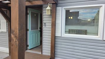 Una casa con puerta azul, una ventana con el letrero 'WELCOME' y un porche de madera.
