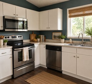 A modern kitchen with white cabinets, stainless steel appliances, and a window with a view of greenery. - Gorgeous 3-bedroom house in tranquil Colorado Springs neighborhood (Colorado Springs)