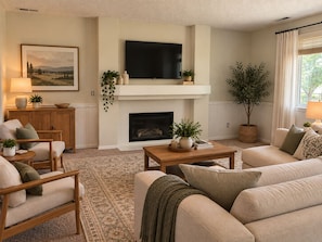 A living room with a fireplace, a television mounted above it, and a large window with curtains. - Gorgeous 3-bedroom house in tranquil Colorado Springs neighborhood (Colorado Springs)