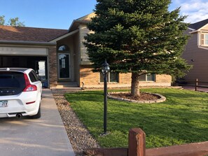 A residential house with a garage, a driveway, a lawn, and a tree. - Gorgeous 3-bedroom house in tranquil Colorado Springs neighborhood (Colorado Springs)