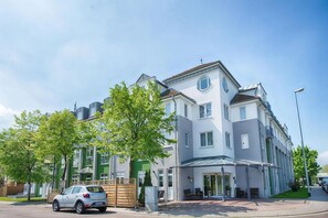 Ein mehrgeschossiges Wohngebäude mit überdachter Eingangspartei und einem parkenden Auto.