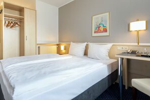 Ein Hotelzimmer mit Bett, Nachttisch, Lampe und einem Bild an der Wand.