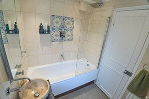 Ein Badezimmer mit Badewanne, Waschbecken, Dusche und einer Tür.