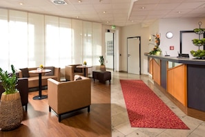 Eine Lobby mit Sofas, einem Empfangstresen und einem roten Teppich.