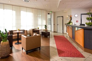 Eine Lobby mit Sofas, einem Empfangstresen und einem roten Teppich.
