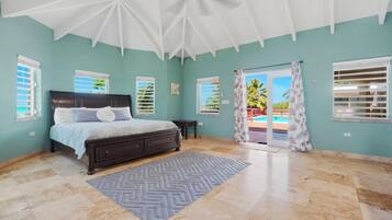 A bedroom with a bed, a ceiling fan, and a view of the outside.