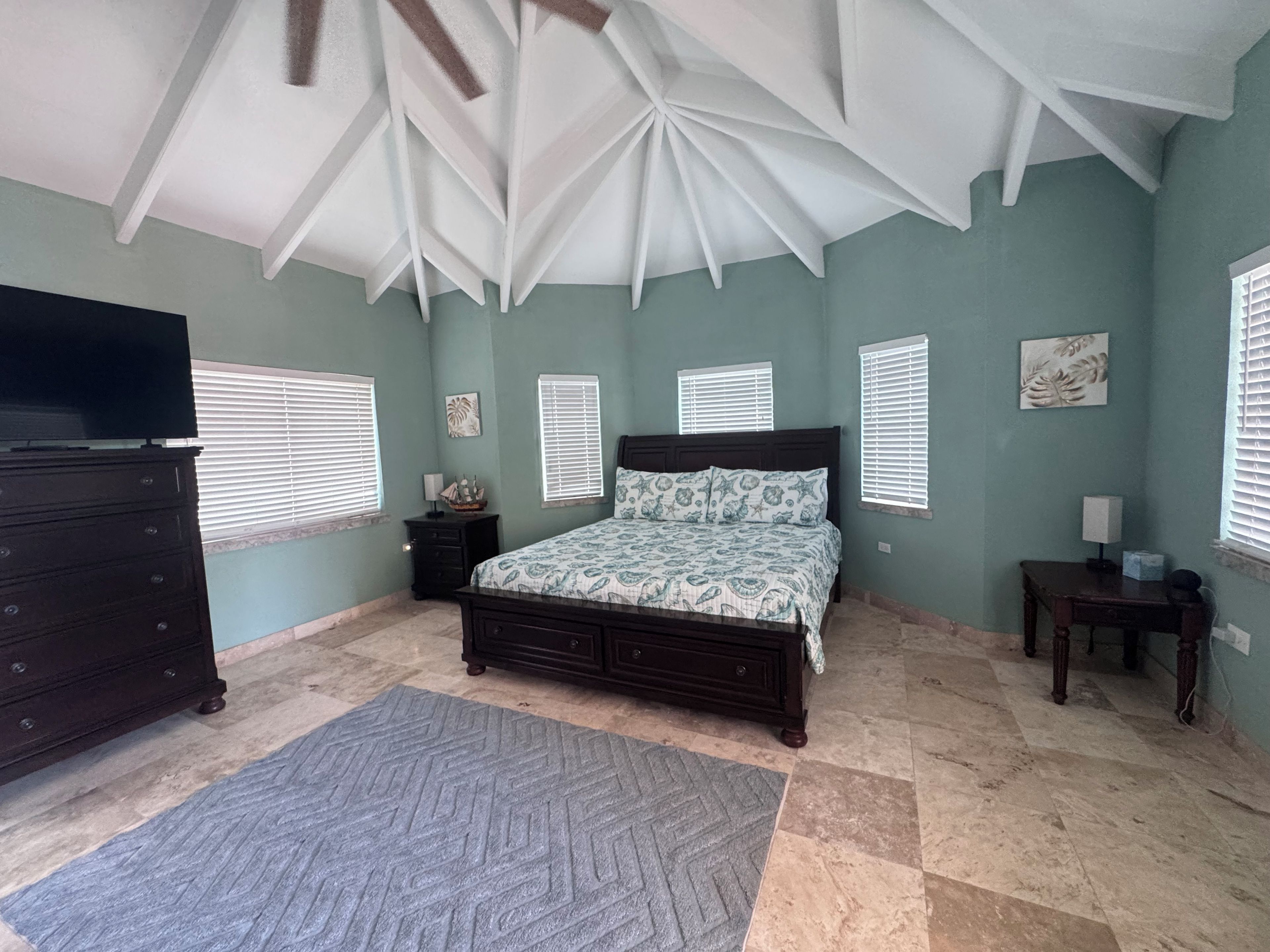 A bedroom with a bed, dresser, and a television.
