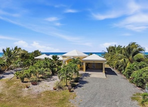 A resort with multiple buildings, a gravel driveway, and palm trees.