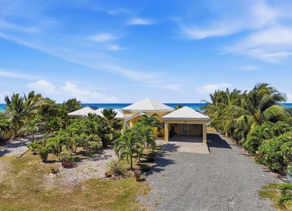 A resort with multiple buildings, a gravel driveway, and palm trees.