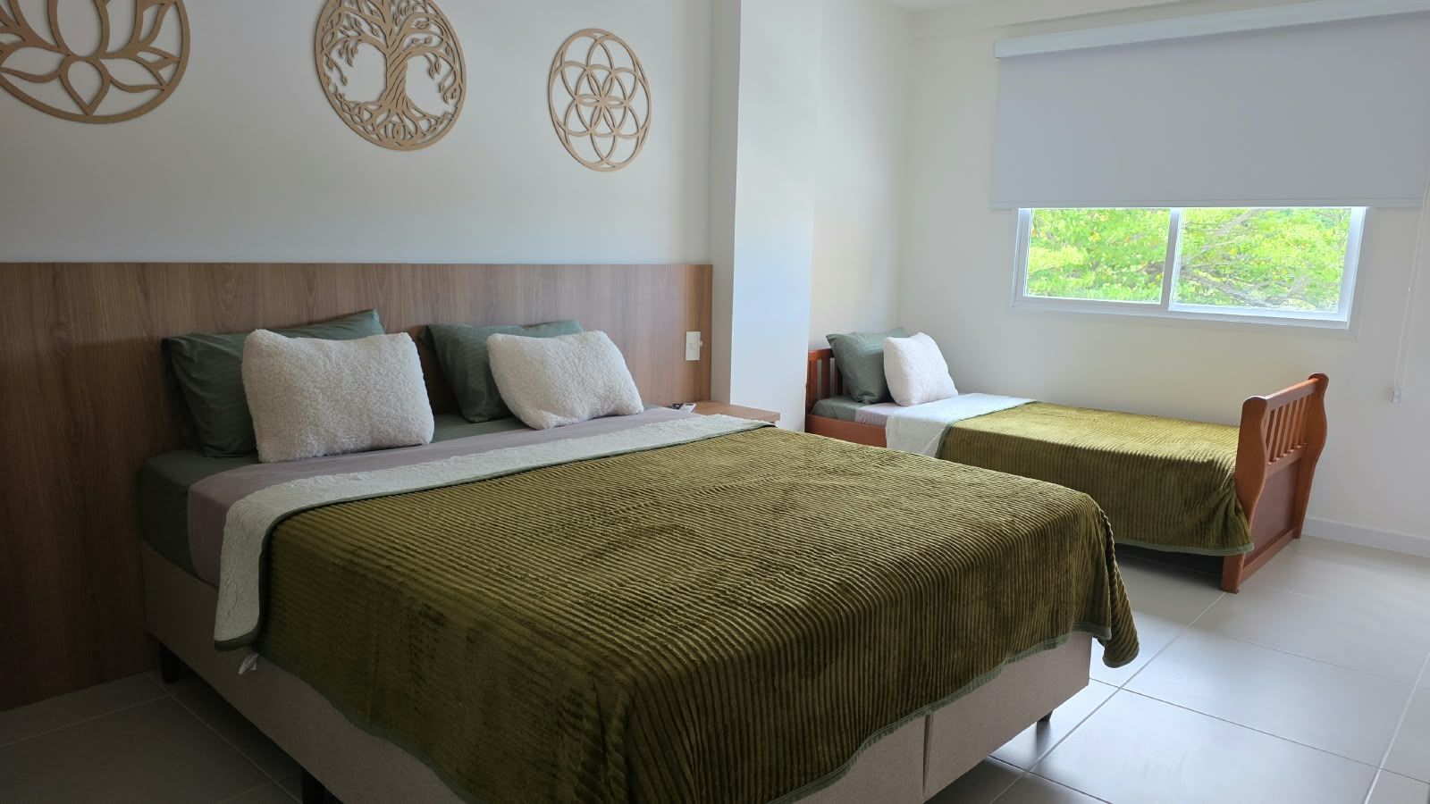 A bedroom with two beds, a window, and decorative wall art.
