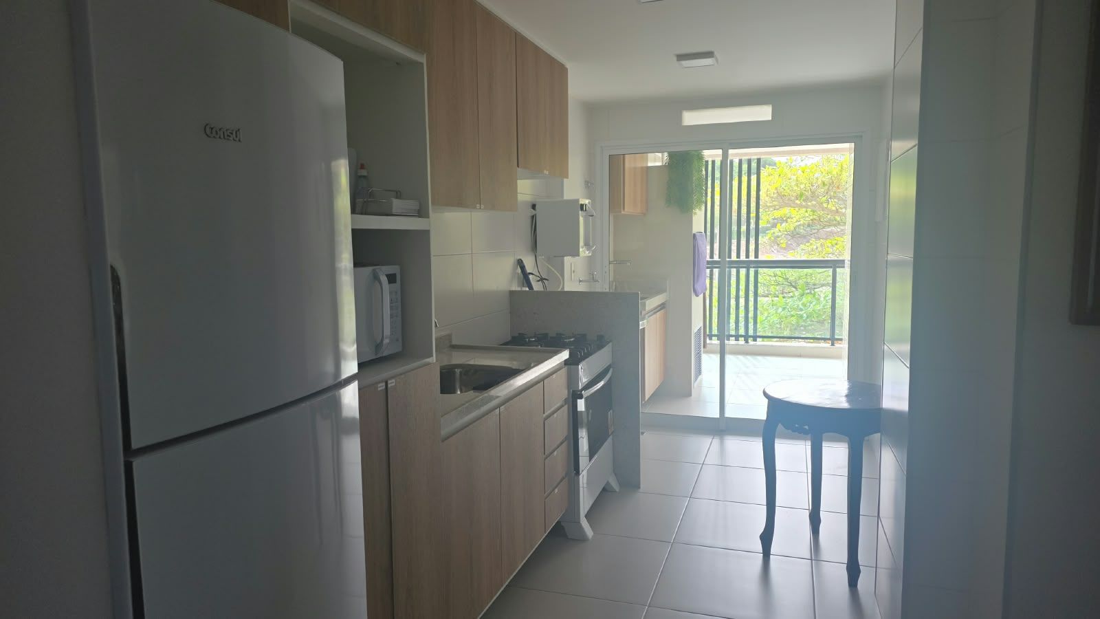 A modern kitchen with a refrigerator, microwave, stove, and sink. There is a dining area with a table and chairs.