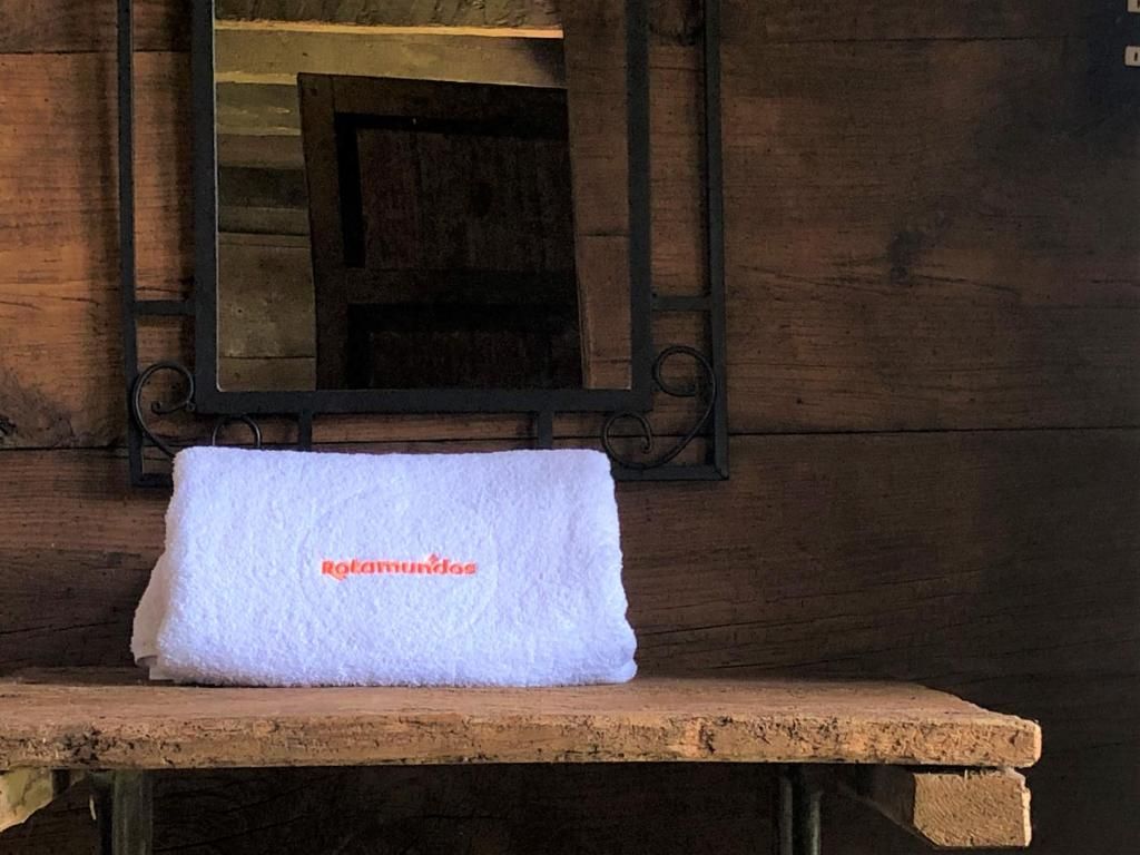 Una toalla blanca con el texto 'Rotamundo' sobre un banco de madera.