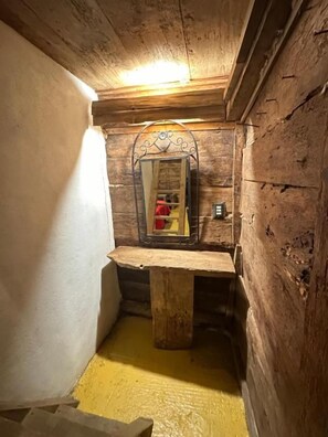 A narrow wooden room with a bench, a mirror, and a small table. - Cabañas del Valle (San Pedro Atmatla)