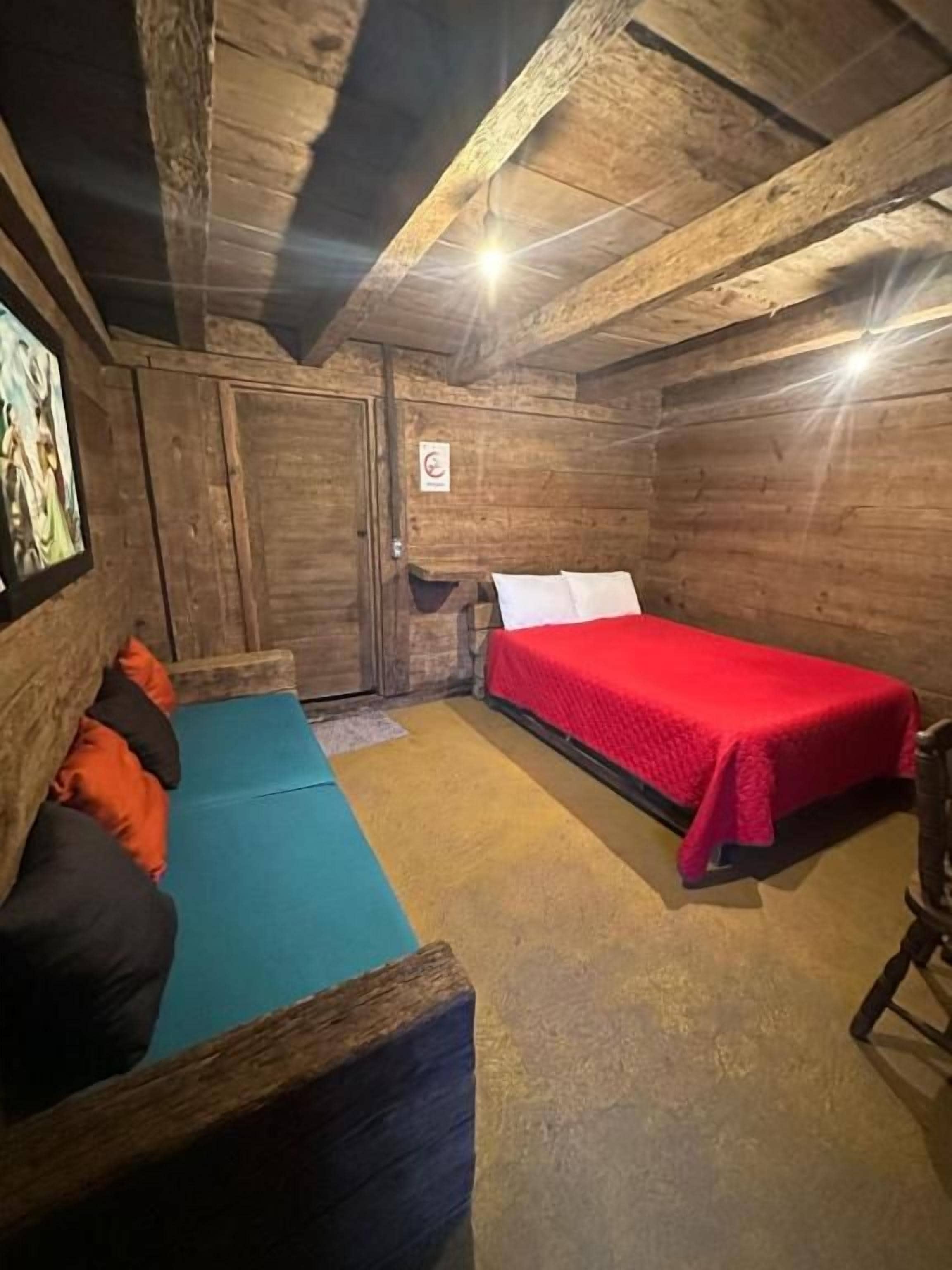 Et værelse med seng, sofa og træloft.