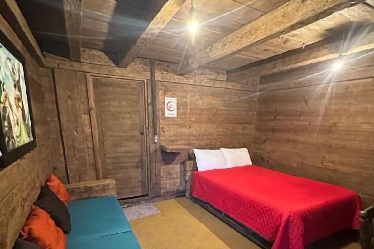A room with a bed, a sofa, and a wooden ceiling.