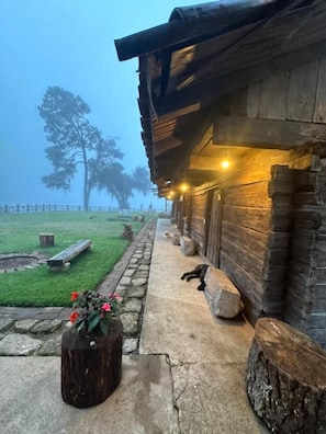 A rustic wooden cabin with a porch, a bench, and a tree in the background. - Cabañas del Valle  (San Pedro Atmatla)
