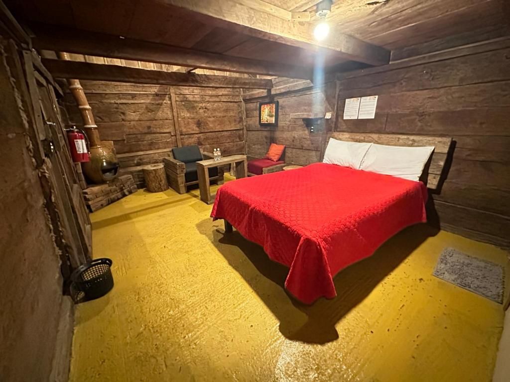 A rustic wooden room with a bed, a table, and a chair.
