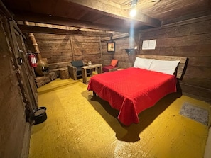 A rustic wooden room with a bed, a table, and a chair. - Cabañas del Valle (San Pedro Atmatla)