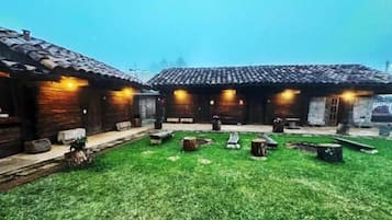 A courtyard with wooden buildings, a grassy area, and stone benches.