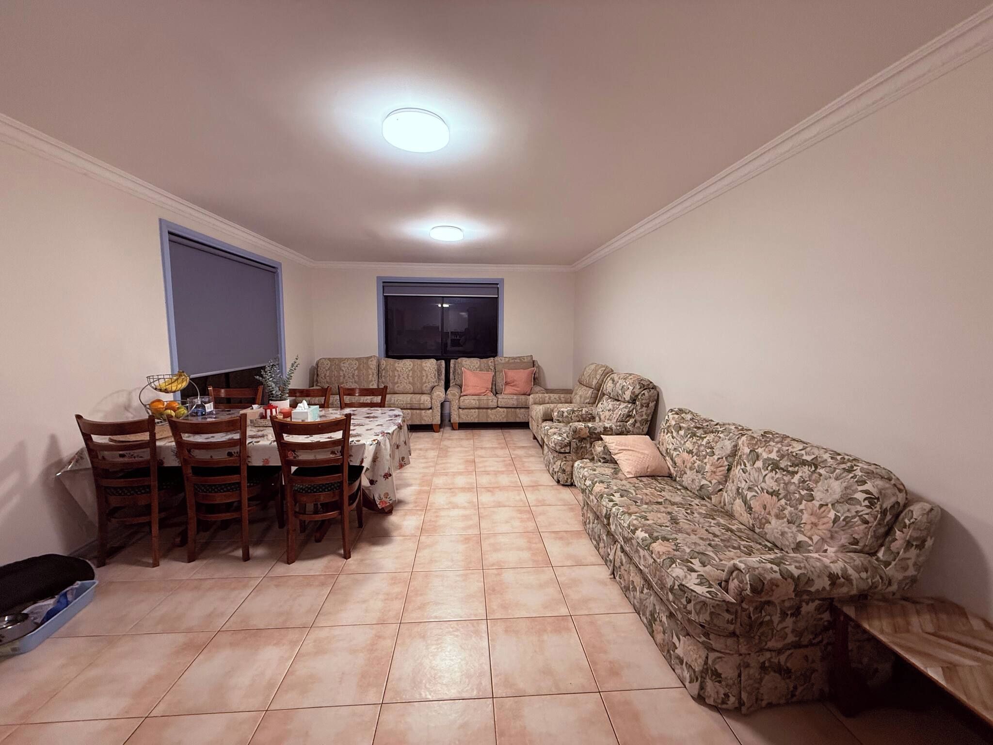 Una sala de estar con comedor, dos sofás, un televisor y piso de baldosas.